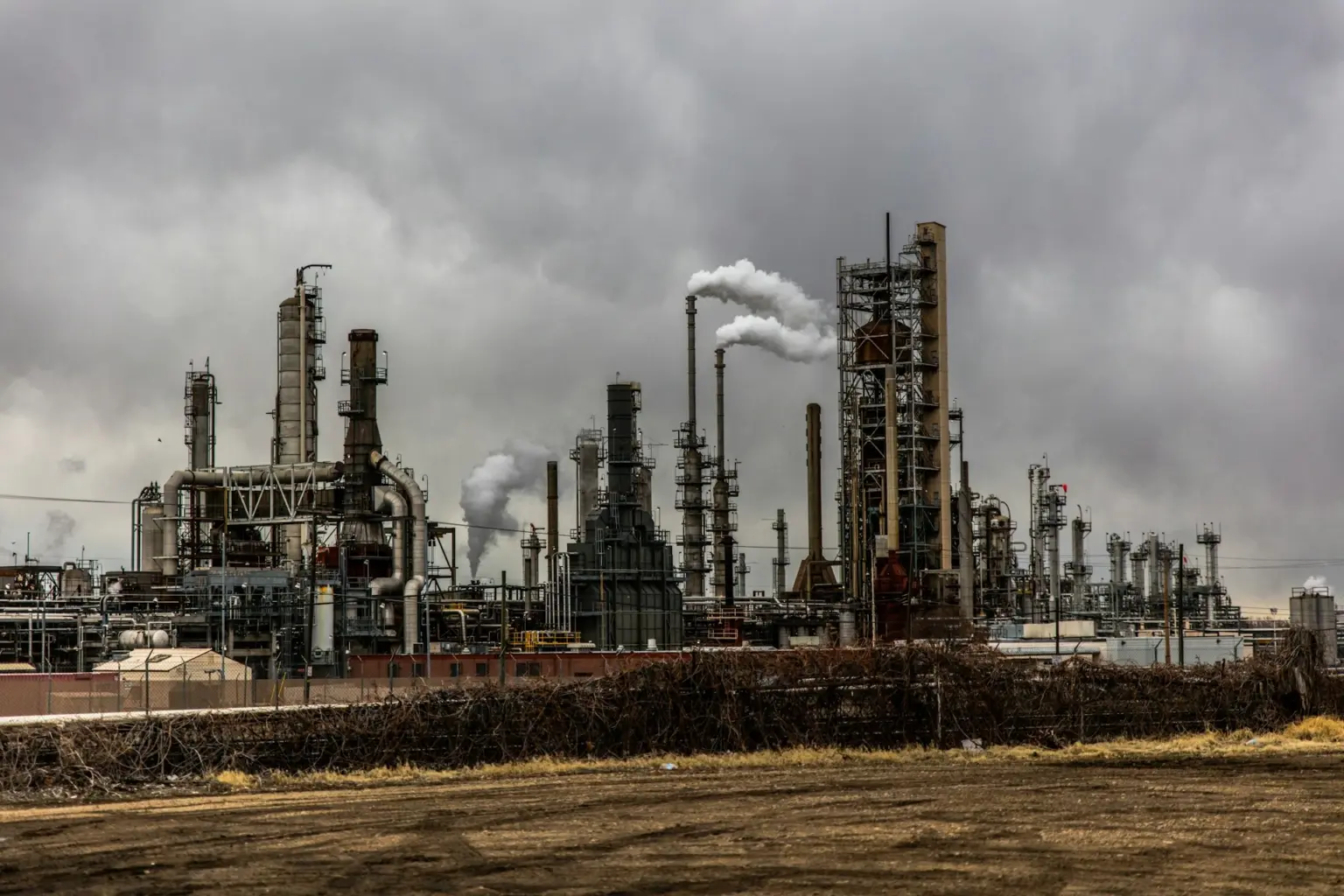 Oil refinery processing towers and smokestacks beneath an overcast sky